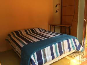 a bed with a striped blanket on it in a room at Recanto do Ipê in Extrema