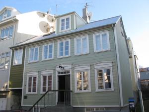 a green house with white windows on a street at Briet Apartments in Reykjavík