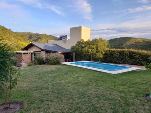 un patio trasero con piscina y una casa en Casa El Drago en La Cumbre