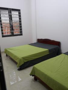 twee bedden in een kamer met groene lakens bij Homestay Hùng My in Ha Giang
