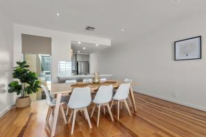 a dining room with a wooden table and white chairs at Sea Star - Aldinga Beach - C21 SouthCoast Holidays in Aldinga Beach