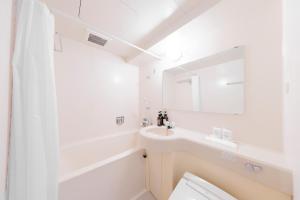 a bathroom with a sink, mirror, and bathtub at Sunny Stone Hotel in Osaka