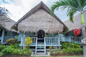a house with a thatched roof and a palm tree at TS Hut Lembongan in Nusa Lembongan