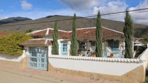 une maison avec une clôture blanche et des arbres dans l'établissement Casa Hotel Santa Helena Boutique, à Villa de Leyva