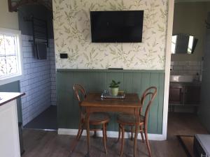 einen Tisch mit Stühlen und einen TV an der Wand in der Unterkunft Peg Cottage in Evandale