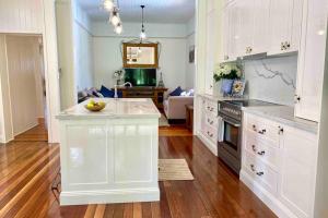 une cuisine avec des placards blancs et un comptoir dans l'établissement Ashbrooke Cottage, à Toowoomba