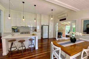 a kitchen with a dining table and a kitchen with white cabinets at Ashbrooke Cottage in Toowoomba