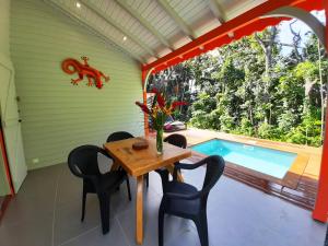 una sala da pranzo con tavolo, sedie e piscina di Caraïbes Cottages Corail piscine privée a 900m de la plage de Grande Anse a Deshaies