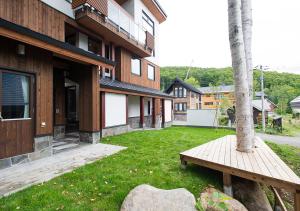 a building with a bench in front of a yard at NISEKO REISE HOUSE ニセコライゼハウス in Kutchan