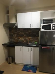 a kitchen with white cabinets and a stainless steel refrigerator at Spacious 1 Bedroom Unit at Centrio Tower in Cagayan de Oro
