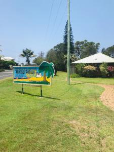a sign in the grass next to a road at Lighthouse Beach Holiday Village in Port Macquarie