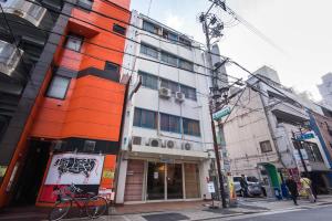 ein orangefarbenes und weißes Gebäude in einer Stadtstraße in der Unterkunft Hostel Q in Osaka