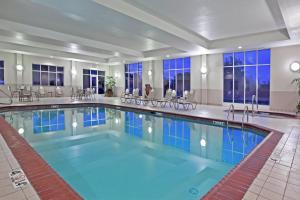 una piscina en un hotel con sillas, mesas y ventanas en Holiday Inn Purdue - Fort Wayne, an IHG Hotel, en Fort Wayne