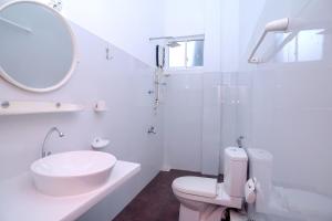 a bathroom with a sink and a toilet and a mirror at Guli Beach Hotel in Hikkaduwa