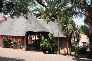 a building with a grass roof with palm trees at Eagles Nest Lodge in Johannesburg