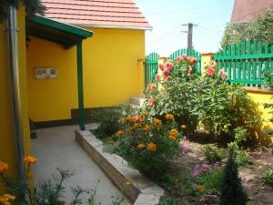 een tuin met bloemen voor een geel huis bij Sárgarigó Vendégház in Bakonybél