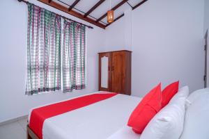 a bedroom with a large white bed with red pillows at Guli Beach Hotel in Hikkaduwa