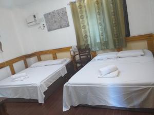 two beds in a room with white sheets at Reyna's the Haven & Gardens in Tagbilaran City