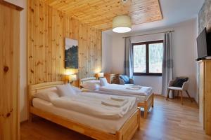 two beds in a room with wooden walls at Rezort Gothal Apartmány a Penzióny in Donovaly