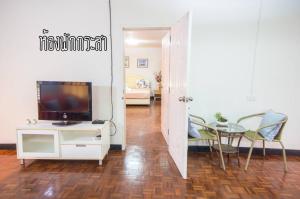 Baan Rug Nam Sai في كلانج: غرفة معيشة مع تلفزيون وطاولة مع كراسي