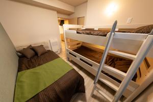 two bunk beds in a small room with a bed at Experience Sapporo in Sapporo