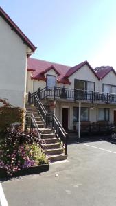 a building with stairs and flowers in a parking lot at Owens Motel in Dunedin