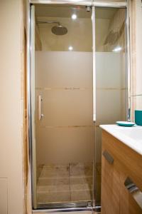 a shower with a glass door in a bathroom at Le Relais du Clocher in Irigny