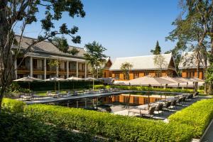 un complejo con piscina, mesas y sombrillas en Avani+ Luang Prabang Hotel, en Luang Prabang