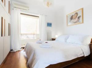 a white bedroom with a large bed and a window at Luxury Athenian Riviera Apartment 135 sqm at Voula in Athens