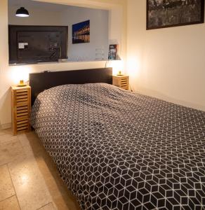 a bedroom with a bed with a black and white comforter at Le Relais du Clocher in Irigny