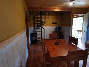 jadalnia z drewnianym stołem i spiralnymi schodami w obiekcie Cabaa Pudomo en Coaripe - Cercana al lago w mieście Coñaripe +1 zdjęcie