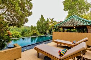 a swimming pool with a chaise lounge and a swimming pool at Tanah Merah Art Resort in Ubud