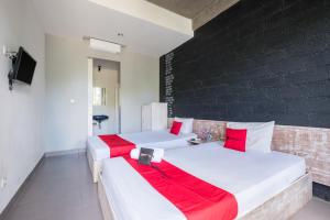 two beds with red pillows in a room at RedDoorz @ Pecatu Ungasan in Uluwatu
