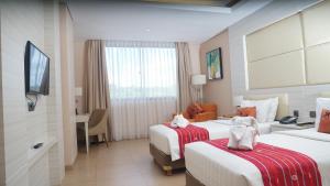 una camera d'albergo con due letti e una televisione di Sotis Hotel Kupang a Kupang