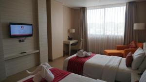 a hotel room with two beds and a flat screen tv at Sotis Hotel Kupang in Kupang