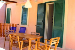 a wooden table and chairs on a patio with green doors at Medusa MDNA in Marina di Modica