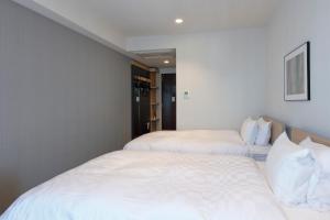 due letti in una stanza con lenzuola bianche di Tmark City Hotel Tokyo Omori a Tokyo