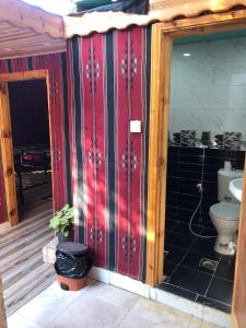 baño con aseo y pared roja en Al-Amer Hostel 1, en Áqaba