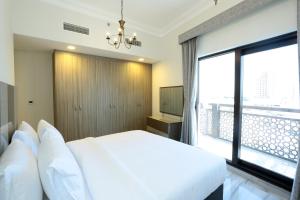 a bedroom with a white bed and a large window at Marbella Holiday Homes in Dubai