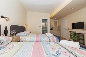 1 dormitorio con 2 camas y cocina con TV. en Bitrak Guest House, en Ohrid