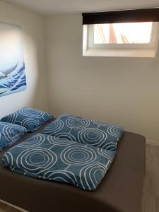 a bed with a blue and white blanket on it at Surf Apartment Stormgade in Hvide Sande