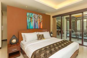 ein Schlafzimmer mit einem Bett und einem Gemälde an der Wand in der Unterkunft Villa Cascade in Seminyak
