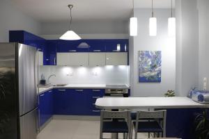 una cocina con armarios azules y una mesa y sillas blancas. en Laconian Collection "Lykourgou 10" en Sparti