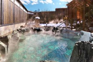 a hot spring in a garden with snow on the ground at Kusatsu-onsen Hotel Resort in Kusatsu