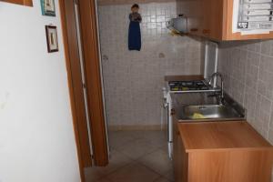 una piccola cucina con un lavandino e una donna sotto la doccia di La Casa Nella Pineta - Gallipoli a Gallipoli Altre 12 foto