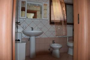 un bagno con lavandino, water e specchio di La Casa Nella Pineta - Gallipoli a Gallipoli