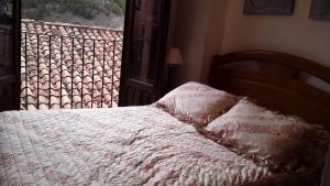 a bed with a white blanket and a window at CASA CENTRO ALBARRACIN in Albarracín