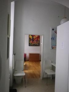 a hallway with white chairs and a painting on the wall at Apartment Dahlia Vienna in Vienna