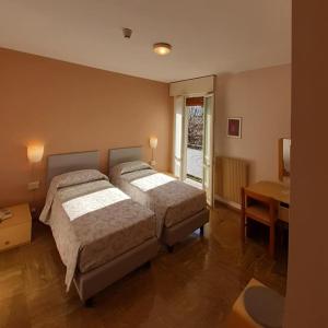 een slaapkamer met 2 bedden, een tafel en een raam bij Albergo Centrale in Tarcento