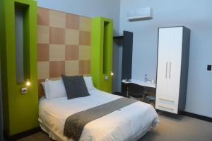 ブルームフォンテーンにあるCity Living Boutique Hotelの緑の壁のベッド1台、デスクが備わるベッドルーム1室が備わります。 +47枚の写真
